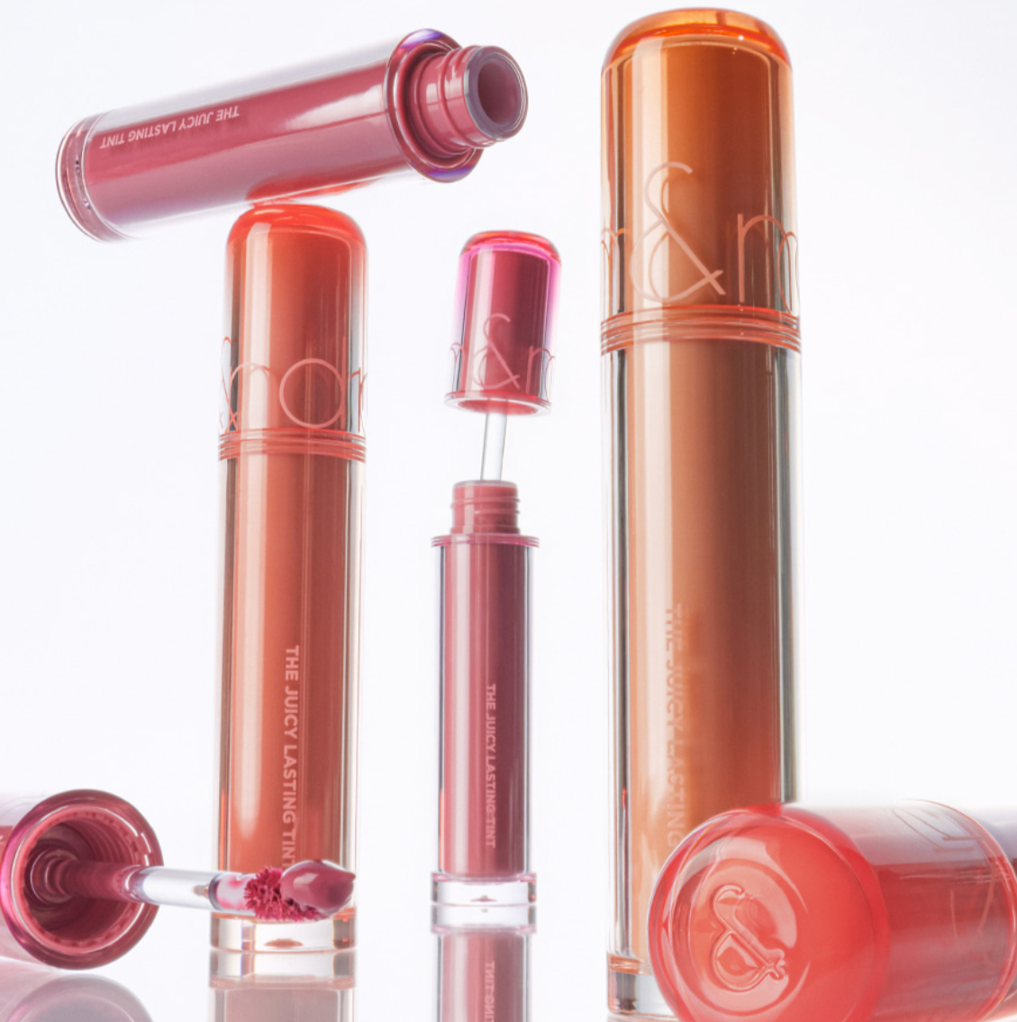 Lip gloss products with visible brand logo on a white background