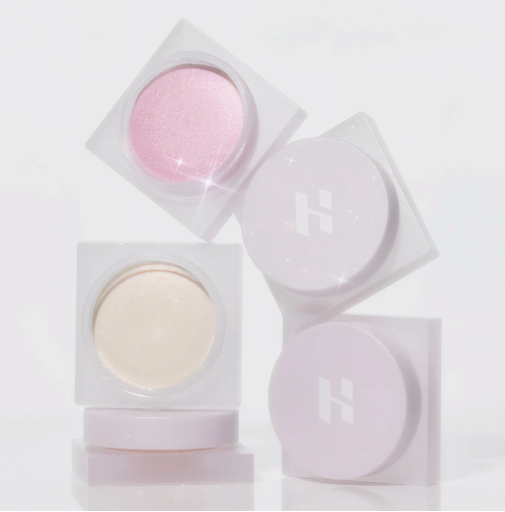 Set of cosmetic powders in clear containers on a light gray background; Holika Holika Luminous Milk Beam Pot for glowing Korean makeup, available at LKR