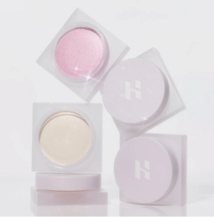 Set of cosmetic powders in clear containers on a light gray background; Holika Holika Luminous Milk Beam Pot for glowing Korean makeup, available at LKR